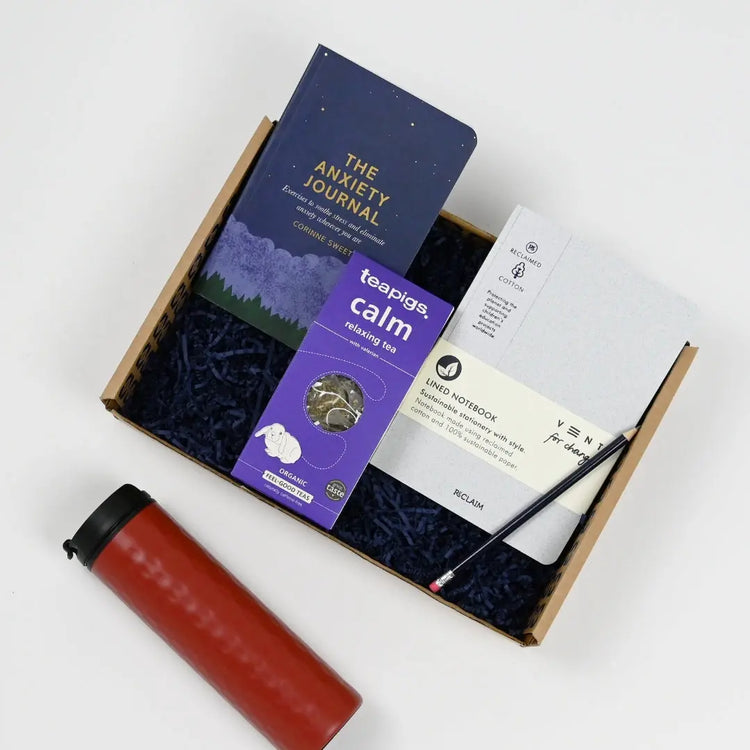 An Anxiety Care Package gift box containing various items including a notebook, the anxiert journal, a thermos, and teapigs calm realxing tea