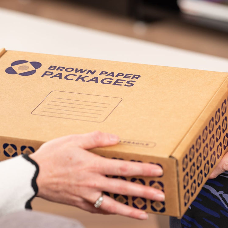 Brown paper packages gift box being handed from a caring gift giver