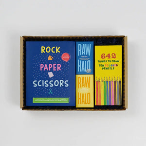 A gift box containing children's art and craft items including a 'ROCK PAPER SCISSORS' game, a 'RAW HALO' drawing challenge, and a set of colored pencils.