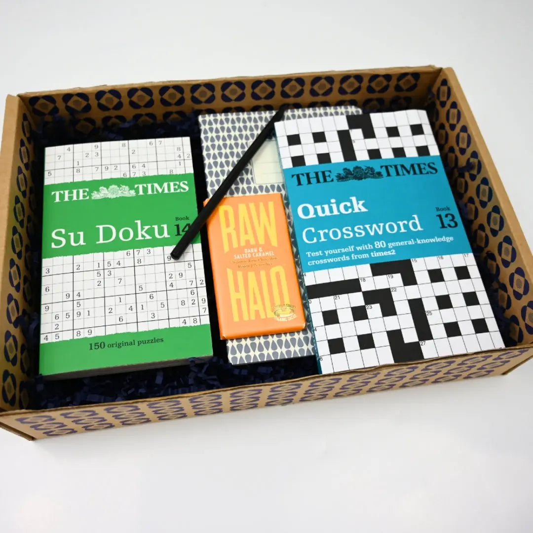 Men's Hospital Care Package containing various items including two books of puzzles (Sudoku and Quick Crossword), a pen, and a package of chocolate.