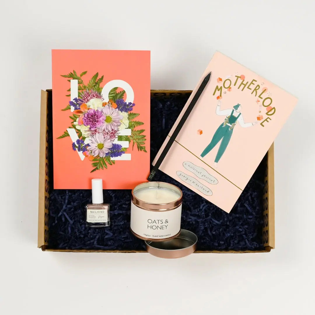 A gift box containing a book titled 'Motherlode', a notebook with 'LOVE' written on the cover, a candle, nail varnish