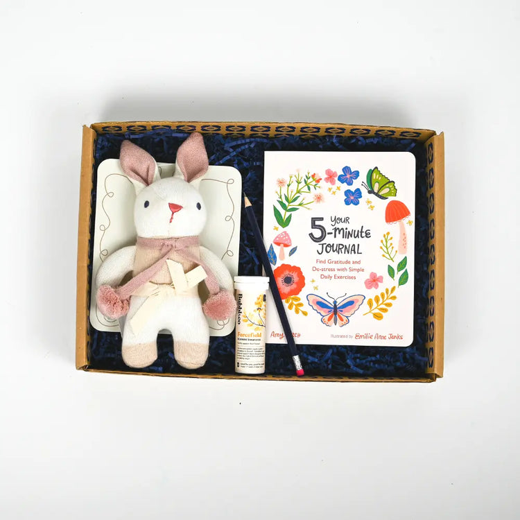 A gift package for new mums containing a plush toy, a journal, and a tube of hand cream, all presented in a decorative gift box with a blue interior.