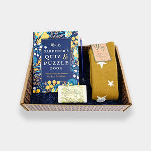 A gift package containing a quiz and puzzle book, a pair of wool socks, and a bar of soap, all with gardening-themed packaging.